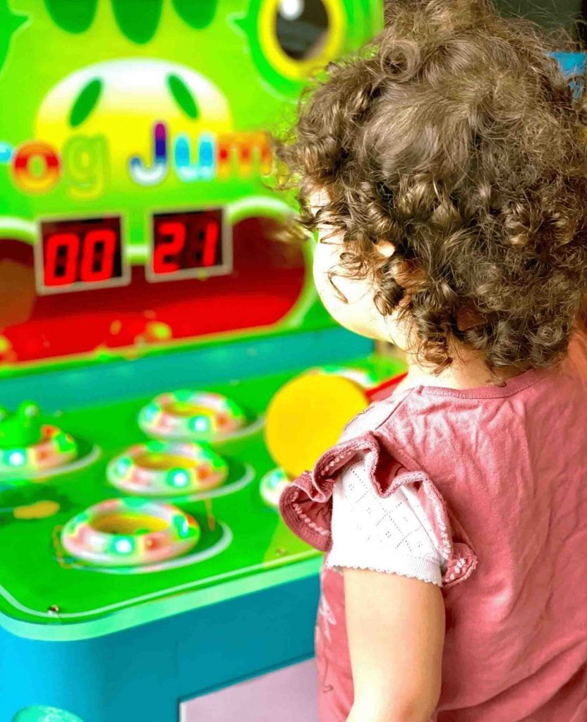 Petite fille qui s'amuse sur un des jeux pour enfants de type tape grenouille